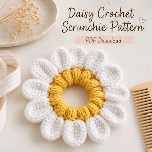 May include: A handmade daisy crochet scrunchie with white petals and a yellow center. The scrunchie is displayed on a light background with the text "Daisy Crochet Scrunchie Pattern PDF Download".