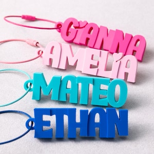 Peut inclure: Quatre porte-clés personnalisés en plastique solide, chacun avec une couleur différente et un anneau en fil métallique assorti. Les noms GIANNA, AMELIA, MATEO et ETHAN sont inscrits en lettres capitales épaisses et en relief, en rose vif, rose clair, bleu sarcelle et bleu.