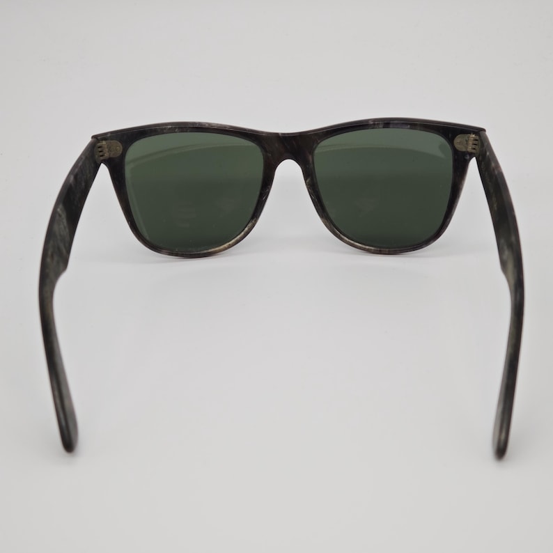 Puede incluir: Gafas de sol con montura oscura y veteada y lentes verdes. El cl&aacute;sico estilo Wayfarer presenta una forma rectangular y patillas gruesas. Las gafas de sol est&aacute;n dise&ntilde;adas para proteger los ojos del sol.