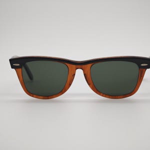 May include: Sunglasses with a classic design. The frames are a warm brown color with black accents on the top and temples. The lenses are a dark green color, providing a stylish and functional accessory.