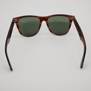 May include: Brown tortoiseshell sunglasses with green lenses. The classic frame design features a rectangular shape and dark brown temples. The sunglasses are displayed against a white background.