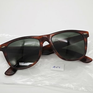 May include: Brown tortoiseshell sunglasses with dark lenses. The sunglasses have a classic, rectangular frame design. A small white tag with the number "A64" is visible.