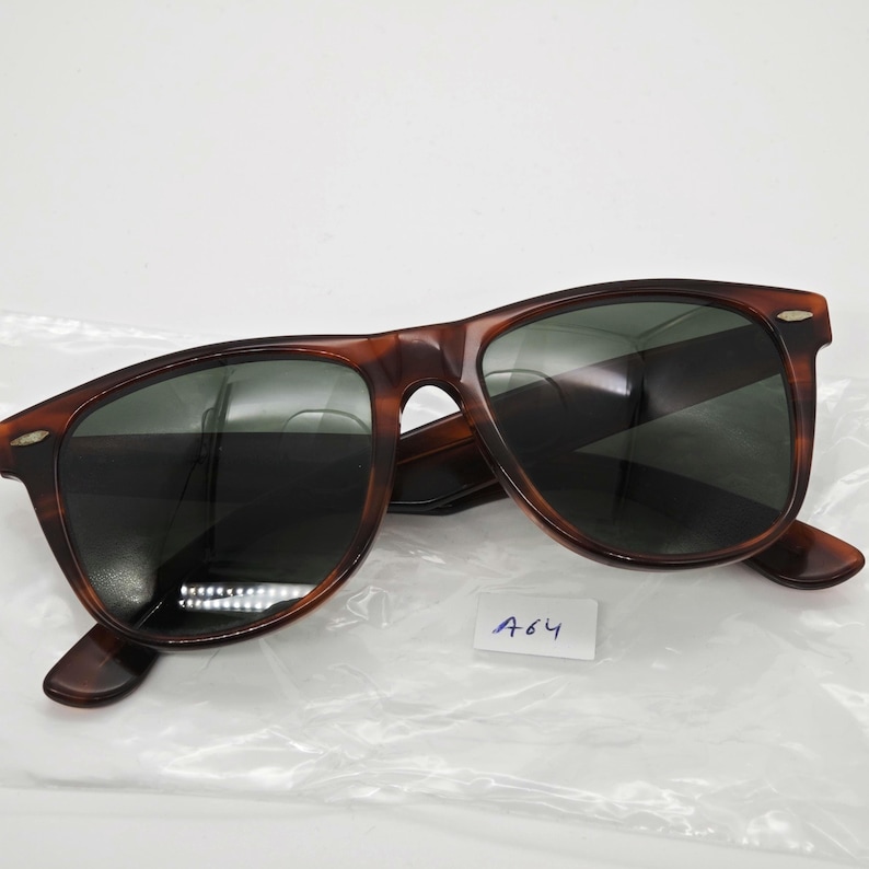 May include: Brown tortoiseshell sunglasses with dark lenses. The sunglasses have a classic, rectangular frame design. A small white tag with the number "A64" is visible.