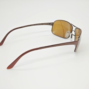 May include: Brown metal sunglasses with rectangular lenses and a classic design. The sunglasses have a thin frame and curved temples for a comfortable fit. The lenses are a warm, amber color, providing a stylish look.