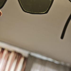 Peut inclure: Lunettes de soleil noires avec une monture dor&eacute;e et des verres vert fonc&eacute;. Les lunettes de soleil ont une forme carr&eacute;e et sont pr&eacute;sent&eacute;es sur un fond neutre. Les branches des lunettes sont noires.