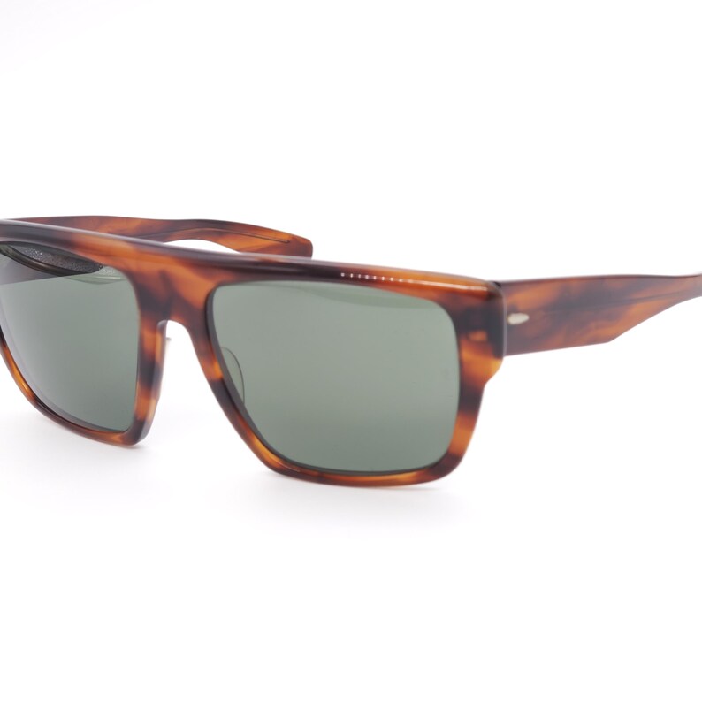 May include: Brown tortoiseshell sunglasses with rectangular frames and green lenses. The sunglasses have a classic design with a slightly curved top bar and thick temples. The lenses are a muted green color, offering a stylish look.