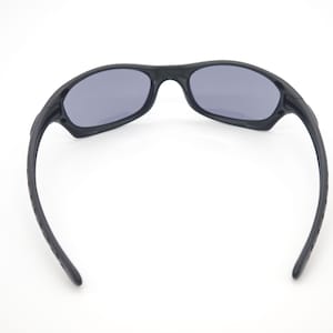 May include: Black sunglasses with gray lenses. The sunglasses have a sporty design with a curved frame and temples. The lenses are oval-shaped and provide protection from the sun.