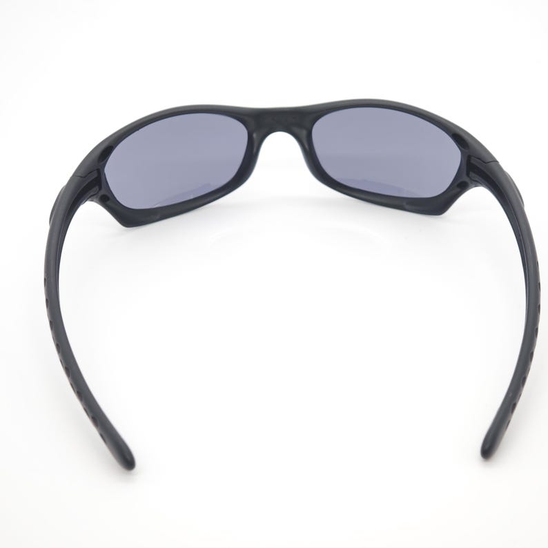 May include: Black sunglasses with gray lenses. The sunglasses have a sporty design with a curved frame and temples. The lenses are oval-shaped and provide protection from the sun.