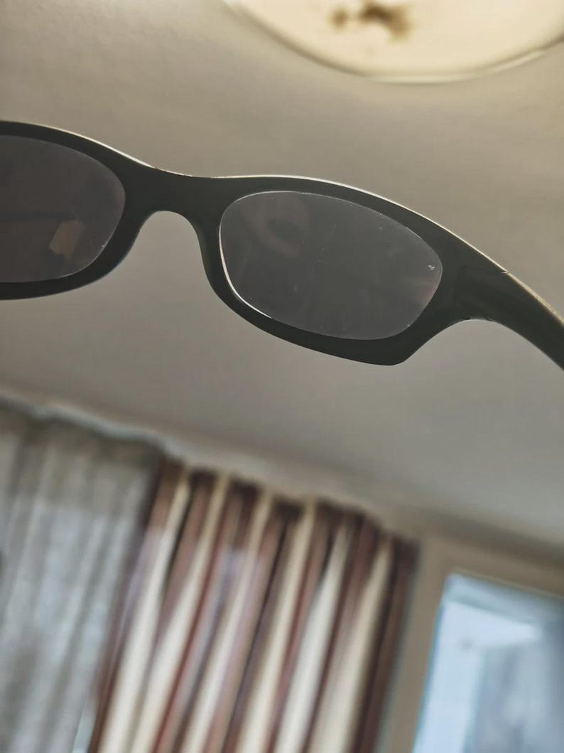 May include: Black sunglasses with a rectangular frame and dark lenses. The sunglasses have a sleek, modern design, suitable for various outdoor activities. The frame appears to be made of a durable material, offering both style and protection from the sun.