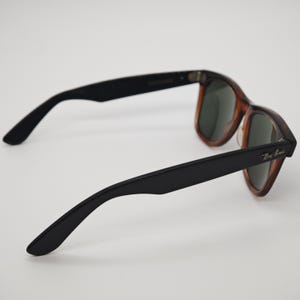 May include: A pair of Ray-Ban sunglasses with a classic design. The frames feature a tortoiseshell pattern with black arms. The lenses are a dark green color. The Ray-Ban logo is visible on the right arm.