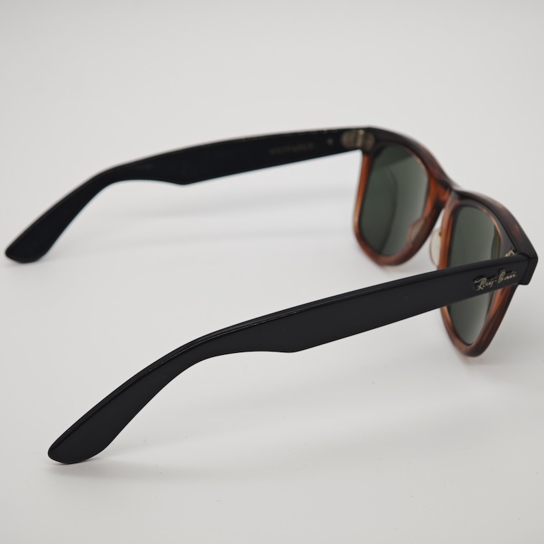 May include: A pair of Ray-Ban sunglasses with a classic design. The frames feature a tortoiseshell pattern with black arms. The lenses are a dark green color. The Ray-Ban logo is visible on the right arm.