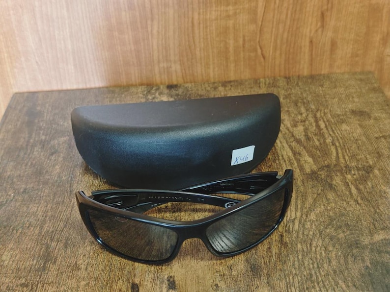K&ouml;nnte beinhalten: Schwarze Sonnenbrille mit passendem schwarzem Etui. Die Sonnenbrille hat ein schlankes, modernes Design mit dunklen Gl&auml;sern und einem stabilen Rahmen. Das ovale Etui bietet Schutz f&uuml;r die Brille.