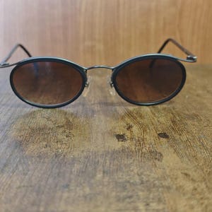 May include: A white ceramic mug with a black handle and the text "But First, Coffee" in a handwritten style. The mug is on a white surface. The mug is 4 inches tall.