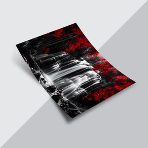 May include: A black and white art print featuring a waterfall cascading down a rocky cliff. The image has a splash of red foliage on the right side, creating a striking contrast. The print is angled, showing a perspective view.