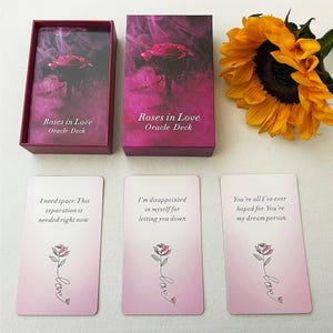 May include: A set of "Roses in Love" oracle cards with a burgundy box and three cards displayed. The box and cards feature a rose image and the text "Roses in Love Oracle Deck". The cards have messages and a rose illustration.