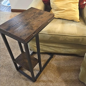 May include: A dark brown side table with a distressed wood top and a lower shelf. The table has a black metal frame and measures approximately 24 inches high, 12 inches wide, and 18 inches deep.
