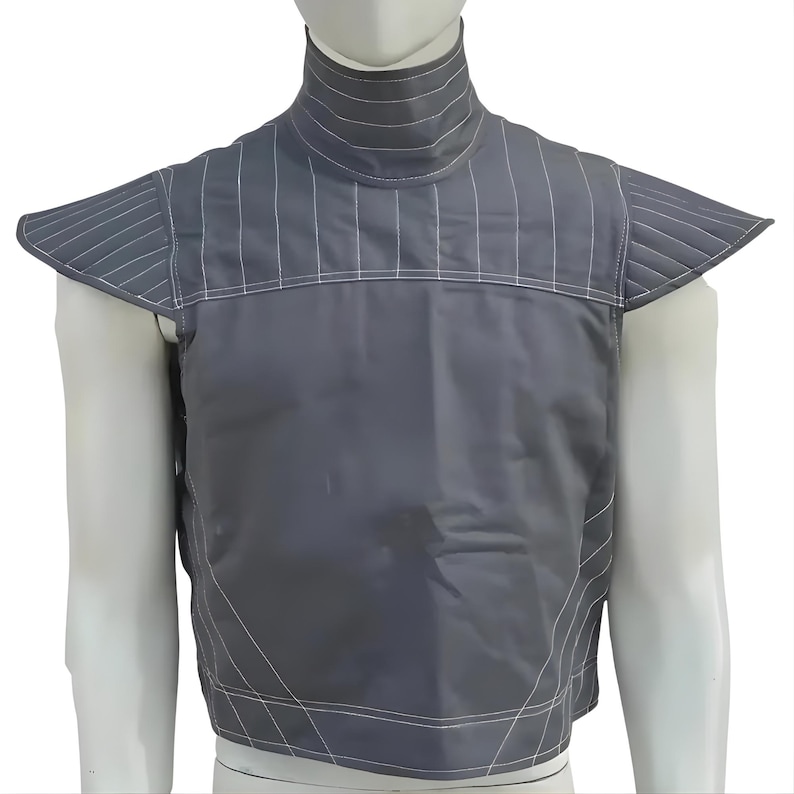 May include: A gray, padded garment with a high collar and shoulder flaps. White stitching accents the seams and vertical lines on the collar and shoulder flaps. The garment appears to be made of a durable, possibly water-resistant material.