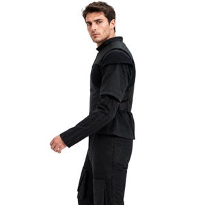 May include: Black jacket with a high collar and a unique design. The jacket features a structured bodice, a belt at the waist, and a pinstriped sleeve. The outfit is completed with black pants.