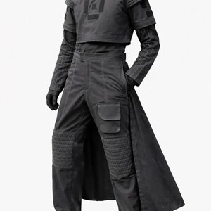 May include: A dark gray futuristic outfit. The ensemble includes a cropped top with a geometric design, long-sleeved striped undershirt, high-waisted pants with knee padding, and a long coat. The outfit is completed with gloves and shoes.