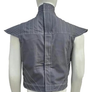 May include: Gray vest with white stitching details. The vest features a high collar and structured shoulder pads. The back of the vest has vertical and horizontal stitching patterns. The vest is made of a smooth, possibly quilted fabric.