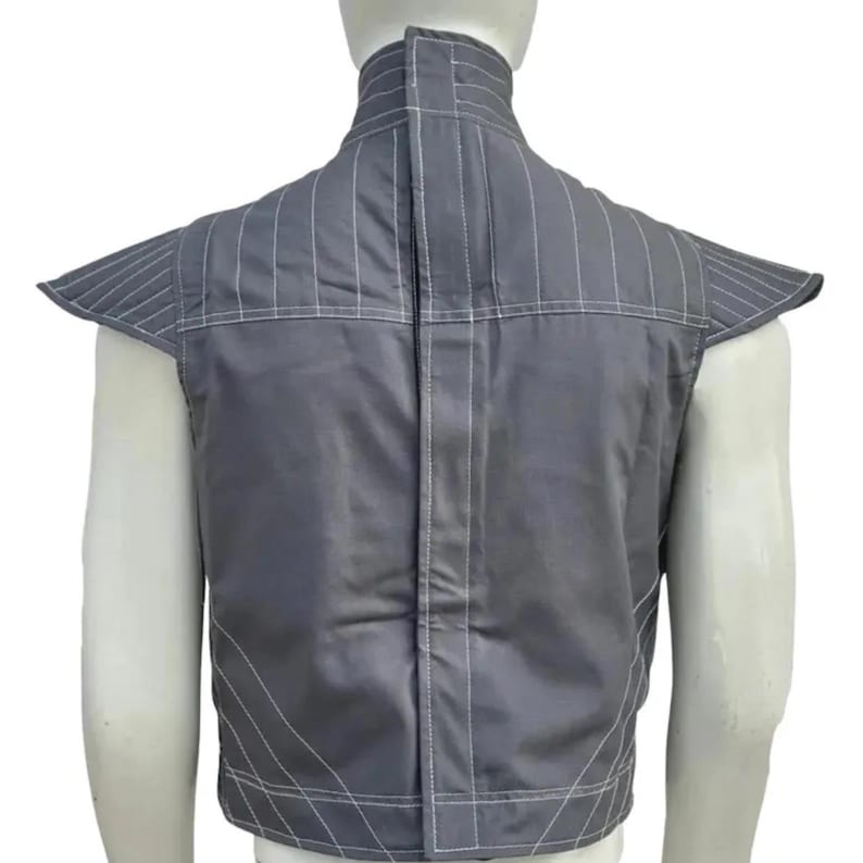May include: Gray vest with white stitching details. The vest features a high collar and structured shoulder pads. The back of the vest has vertical and horizontal stitching patterns. The vest is made of a smooth, possibly quilted fabric.