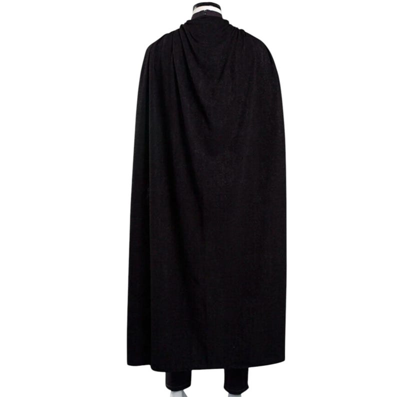 May include: A long, black cape with a draped hood. The cape is made of a dark, possibly wool-like material, and falls to the ankles. The image is a rear view, showing the full length of the garment.