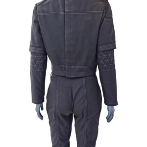 K&ouml;nnte beinhalten: Dunkelgrauer Overall mit wei&szlig;en Steppn&auml;hten. Die Jacke ist kurz geschnitten und hat geometrische Muster an den &Auml;rmeln. Die Hose hat einen hohen Bund und eine taillierte Passform. Der Overall ist aus strapazierf&auml;higem Stoff.