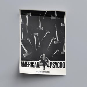 K&ouml;nnte beinhalten: Schwarz-wei&szlig; Filmplakat f&uuml;r "American Psycho" mit einem Mann im Anzug, der in einem Stuhl sitzt, umgeben von &Auml;xten. Der Titel ist prominent dargestellt, mit dem Text "A film by Mary Harron" darunter.