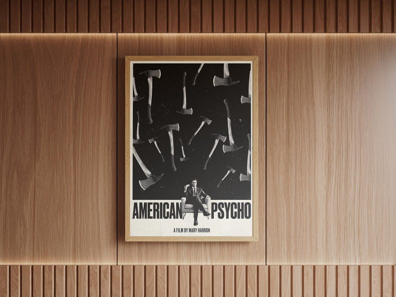 K&ouml;nnte beinhalten: Ein gerahmtes Poster mit dem Titel "AMERICAN PSYCHO" und einem Schwarz-Wei&szlig;-Bild von &Auml;xten und einem Mann im Anzug. Das Poster h&auml;ngt an einer Holzwand.