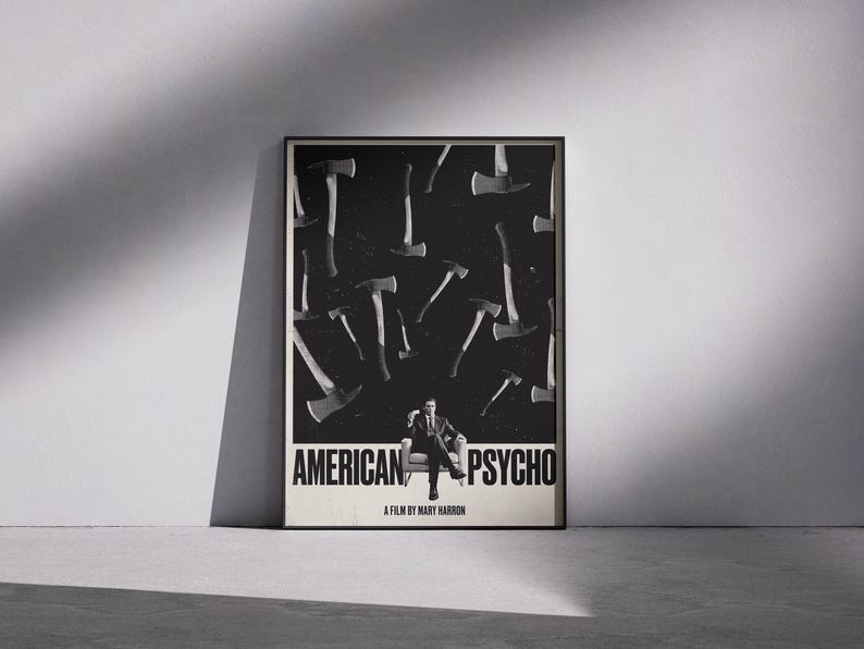 Peut inclure: Affiche encadrée en noir et blanc du film "American Psycho". L'affiche présente un homme assis dans un fauteuil, entouré de haches sur fond sombre. Le titre du film est affiché en gros caractères.