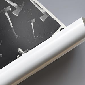 K&ouml;nnte beinhalten: Schwarz-Wei&szlig;-Kunstdruck mit einem sich wiederholenden Muster von &Auml;xten auf dunklem Hintergrund. Ein Mann im Anzug ist teilweise sichtbar. Der Druck ist teilweise gerollt.