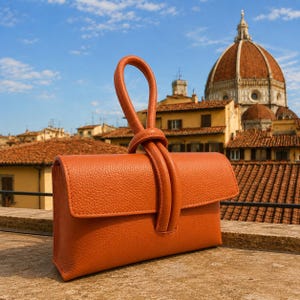 Borsa in pelle arancione, vera pelle di vitello Made in Italy, manico annodato e tracolla.