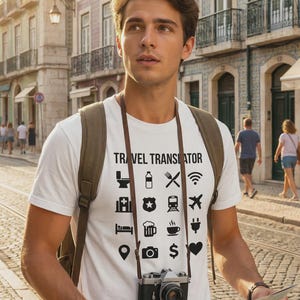 Puede incluir: Una camiseta blanca con el texto "TRAVEL TRANSLATOR" e iconos de viaje. La persona lleva una mochila y sostiene un mapa y una cámara. El fondo muestra una escena de calle europea.