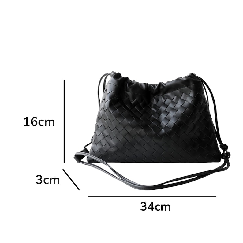 Puede incluir: Bolso negro de cuero tejido con cord&oacute;n. El bolso mide 34 cm de ancho, 16 cm de alto y 3 cm de profundidad. Tiene un cierre de cord&oacute;n y una correa para el hombro. El bolso est&aacute; hecho de cuero tejido.