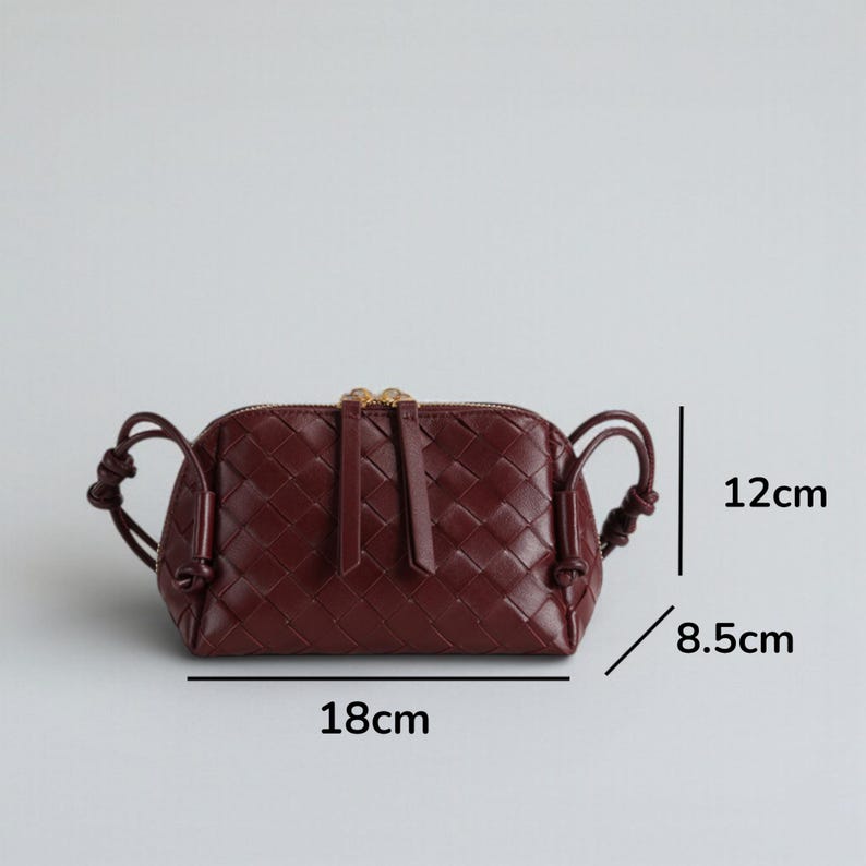 Pu&ograve; includere: Borsa a mano in pelle intrecciata bordeaux con cerniera superiore e manici annodati. La borsa misura 18 cm di lunghezza, 12 cm di altezza e 8,5 cm di larghezza. Ha una cerniera dorata e un tirazip in pelle abbinato.