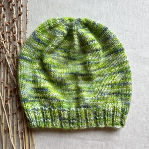 May include: A green, white and grey striped knitted beanie hat.