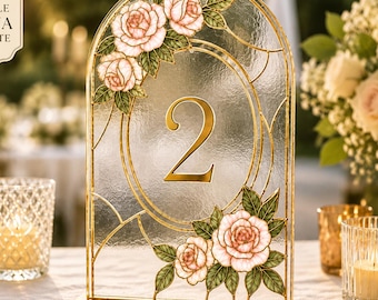 Puede incluir: Un letrero de número de mesa arqueado con el número 2 en dorado, rodeado de rosas rosadas y hojas verdes estilo vitral con un marco dorado. El texto "EDITABLE CANVA TEMPLATE" está impreso en la esquina superior izquierda de la imagen.