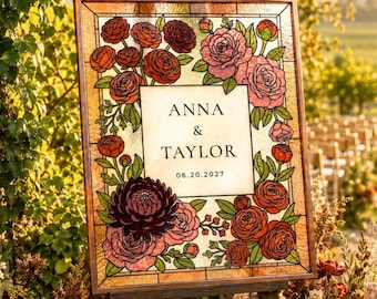 Puede incluir: Un letrero rectangular de vidrieras con un borde floral de rosas y dalias rojas, rosas y burdeos con hojas verdes. El panel central muestra el texto ANNA & TAYLOR y la fecha 20.06.2027 en una fuente serif negra sobre un fondo de color crema.