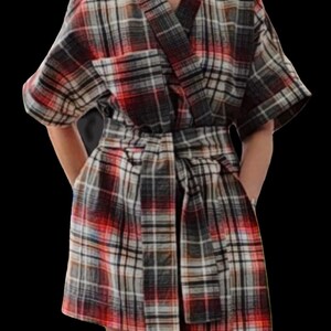 May include: A plaid kimono-style robe in red, black, white, and grey. The robe has a V-neck, short sleeves, and a matching belt. The fabric appears to be a soft, woven material. The robe is knee-length and has pockets.