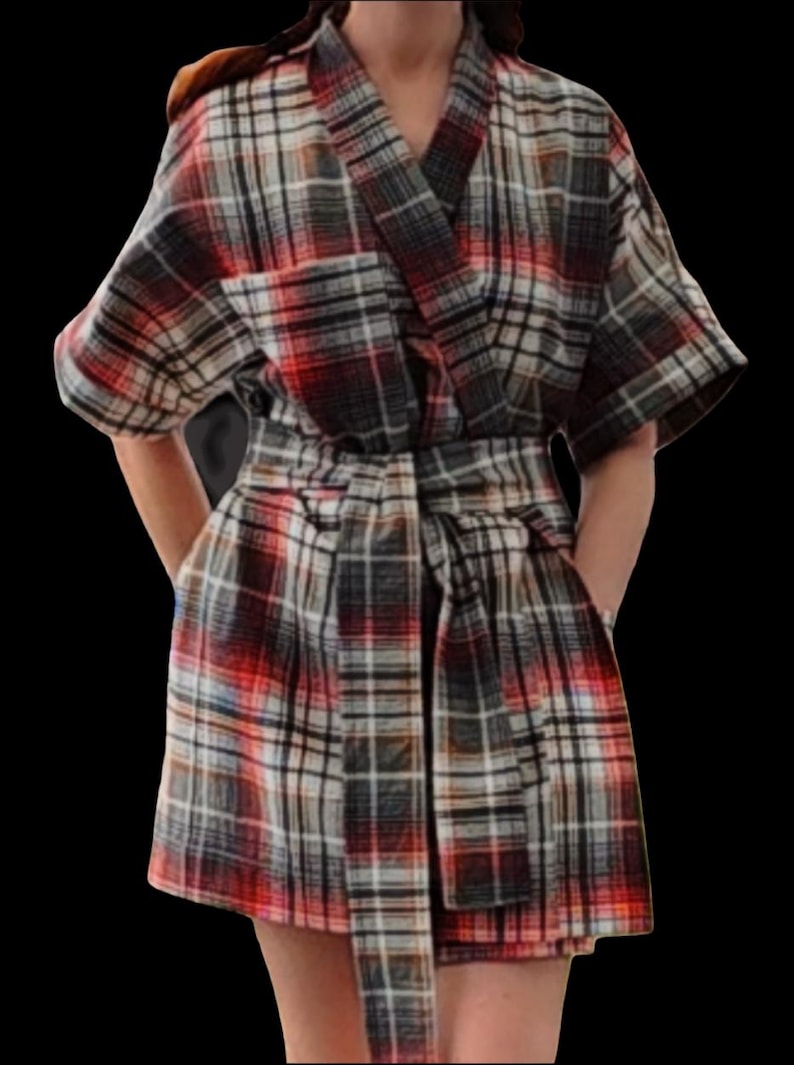May include: A plaid kimono-style robe in red, black, white, and grey. The robe has a V-neck, short sleeves, and a matching belt. The fabric appears to be a soft, woven material. The robe is knee-length and has pockets.