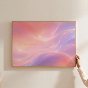 Op de afbeelding: Een rechthoekige wandkunstprint in een dunne houten lijst met een abstract, vloeiend ontwerp met gemengde gradiënten van zachte roze, perzik en lavendeltinten. De tekst "Soft Life Sweet Escape Serenity" is gedrukt in kleine, lichtgouden letters.