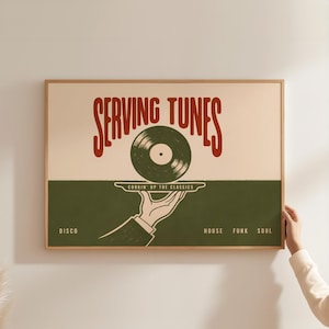 Pode incluir: Um poster emoldurado com um design retro. O poster apresenta o texto "SERVING TUNES" em vermelho, com um gráfico de disco de vinil. Abaixo, uma mão segura uma bandeja com o disco, e as palavras "DISCO, HOUSE, FUNK, SOUL" são impressas.