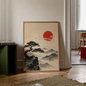 Può includere: Una stampa incorniciata di un paesaggio giapponese. L'opera raffigura un sole rosso, montagne e un albero su una scogliera. Gli uccelli volano nel cielo. La stampa ha una cornice in legno ed è esposta in interni.
