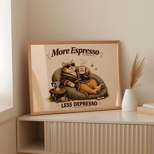 Könnte beinhalten: Ein gerahmter Druck mit einer entspannten Katze mit Sonnenbrille und Bademantel, die eine Kaffeetasse hält. Der Druck lautet "More Espresso, Less Depresso". Ein kleiner Tisch mit einer Kaffeemaschine und einer Schüssel mit Leckereien befindet sich neben der Katze.