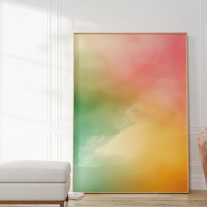 Könnte beinhalten: Ein rechteckiger Wandkunstdruck mit einem weichen, abstrakten Farbverlauf aus gemischten Tönen wie leuchtendem Pink, warmem Gelb und tiefem Grün. Das Kunstwerk ist in einen dünnen, hellen Holzrahmen gefasst und zeigt einen sanften, wolkenartigen Übergang der Farben über die gesamte Druckfläche.