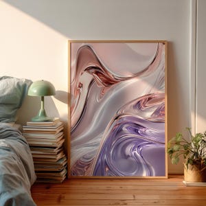 Könnte beinhalten: Abstrakter Kunstdruck in einem Holzrahmen. Das Kunstwerk zeigt fließende, glänzende Formen in Rosa-, Silber- und Lilatönen. Der Druck wird auf einem Holzboden an einer Wand gelehnt präsentiert, mit einer grünen Lampe und Büchern in der Nähe.