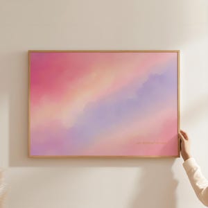 Könnte beinhalten: Ein rechteckiger Wandkunstdruck in einem hellen Holzrahmen mit einem weichen, verlaufenden Gradienten aus Rosa-, Pfirsich- und Lavendeltönen. Das abstrakte Design ähnelt einem dunstigen, ätherischen Himmel mit fließenden Farbübergängen.