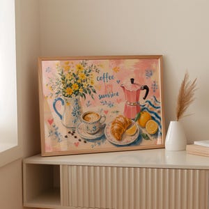 Könnte beinhalten: Ein gerahmter Kunstdruck mit einer gemalten Frühstücksszene, die eine Vase mit gelben Blumen, eine Tasse Kaffee, ein Croissant, eine rosa Espressokanne und Zitrusfrüchte zeigt. Der Text "coffee joy sunshine" ist in blauer Schrift zu sehen.