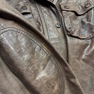 Primo piano giacca Burberry in pelle marrone multitasche, chiusura con zip e bottoni. Cintura in vita.