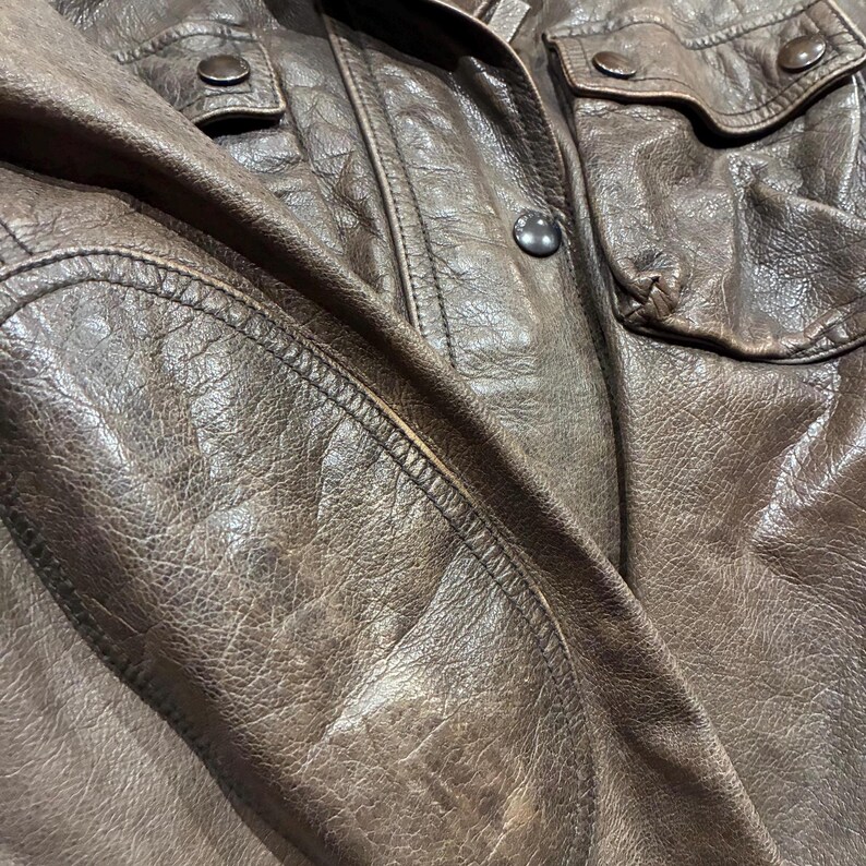 Primo piano giacca Burberry in pelle marrone multitasche, chiusura con zip e bottoni. Cintura in vita.